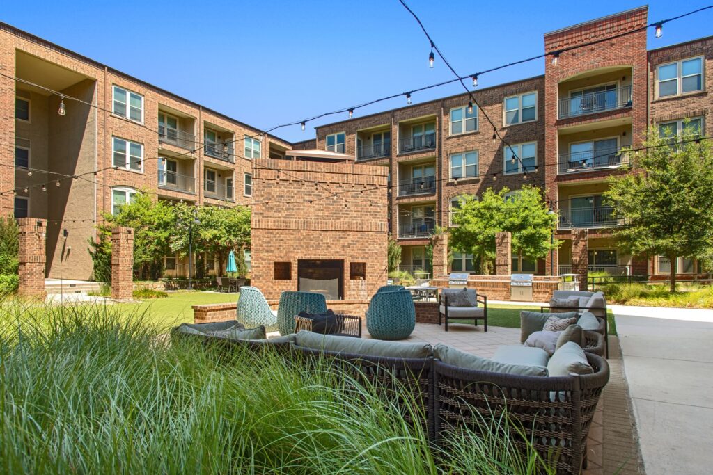 exterior courtyard with string lights and seating with outdoor fireplace centered